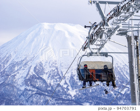 リフトに乗るスノーボーダーと積雪の羊蹄山 (北海道、ニセコ) リフトに乗るスノーボーダーと積雪の羊蹄山 (北海道、ニセコ) 94703791