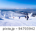 快晴のスキー場で樹氷原の中を滑走する人々 (山形県、蔵王温泉スキー場) 94703942