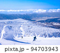 快晴のスキー場で樹氷原の中を滑走する人々 (山形県、蔵王温泉スキー場) 94703943