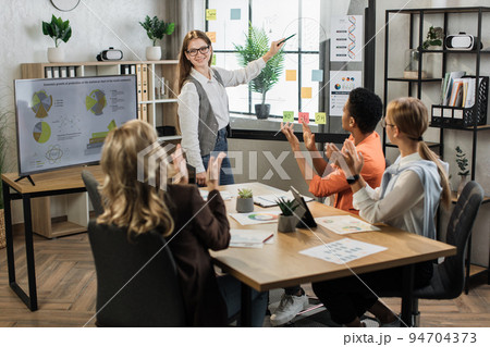 Caucasian woman in formal wear pointing on glass board with charts and graphs 94704373
