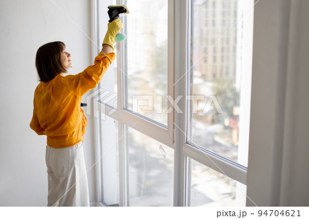 Woman washes window in apartment 94704621