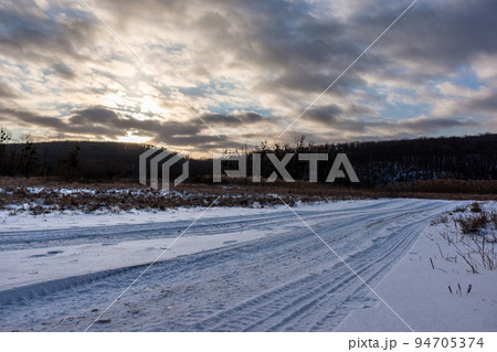 Snowy white rural road in wintry countryside 94705374