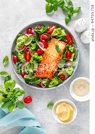 Grilled salmon fish fillet and fresh green leafy vegetable salad with tomatoes, red onion and broccoli. Healthy food. Ketogenic lunch. Top view 94705758