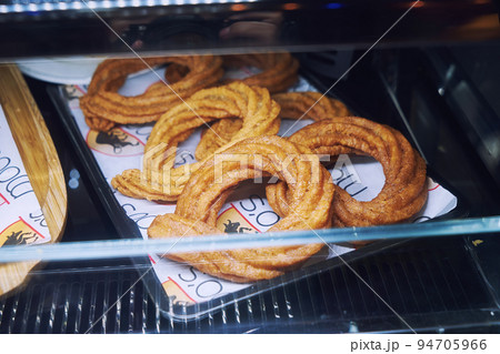 Sweet baked churros pretzel with cinnamon and caramel on counter in street cafe Sweet baked churros pretzel with cinnamon and caramel on counter in street cafe 94705966