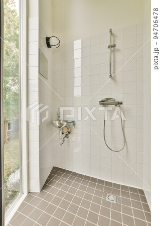 Sink base cabinet and mirror cabinet in white tiled bathroom with wall hung toilet 94706478