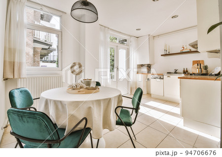 Interior of light kitchen and dining room with balcony doors in contemporary apartment at daytime Interior of light kitchen and dining room with balcony doors in contemporary apartment at daytime 94706676