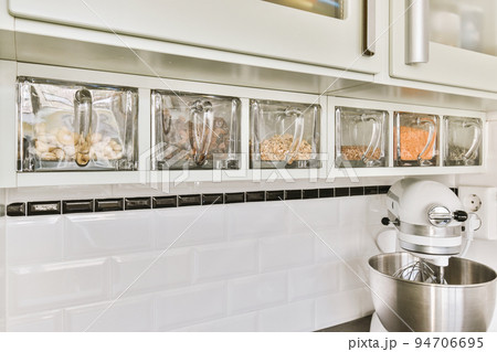 Fragment of interior of light narrow home kitchen with minimalist style white furniture with sink and stove 94706695