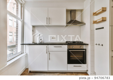Well organized small home kitchen interior with sink under window and light furniture with stove and fridge in urban apartment Well organized small home kitchen interior with sink under window and light furniture with stove and fridge in urban apartment 94706783