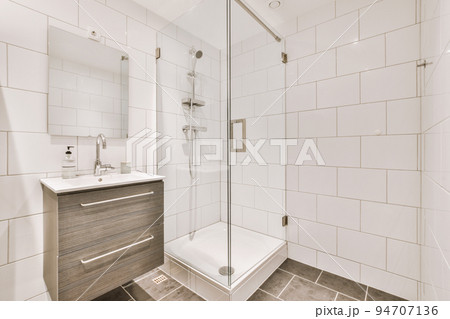 Sinks with mirrors and shower box with glass door in modern bathroom with white tiled walls 94707136