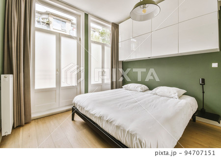 Home interior design of bedroom with bed and wooden wardrobe placed in corner near window in modern apartment Home interior design of bedroom with bed and wooden wardrobe placed in corner near window in modern apartment 94707151