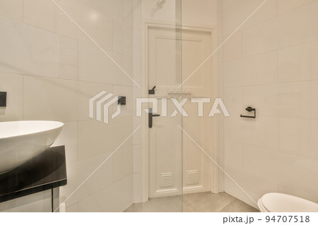 Flush toilet located between sink and shower in small tiled bathroom of contemporary apartment Flush toilet located between sink and shower in small tiled bathroom of contemporary apartment 94707518