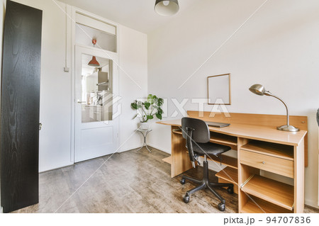 Comfortable chair placed near table with computer monitors against blank whiteboard and mirror in light home office in contemporary flat Comfortable chair placed near table with computer monitors against blank whiteboard and mirror in light home office in contemporary flat 94707836
