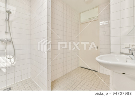 Wall hung toilet and small sink in corner in lavatory room with beige tile 94707988