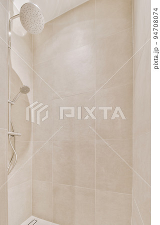 Shower faucets attached to tiled wall near glass partition and ornamental curtail in washroom at home 94708074