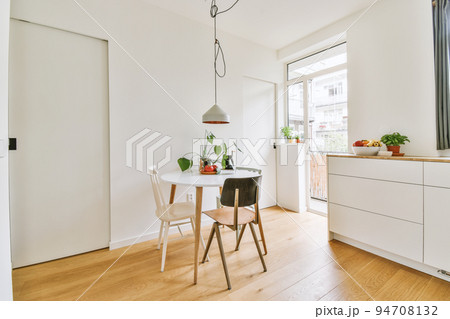 Home interior design of modern loft apartment with open kitchen in minimalist style and spacious dining zone with table and chairs 94708132