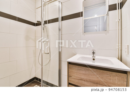 Bathroom with white tiled walls and open shower near sink with toilet in light Bathroom with white tiled walls and open shower near sink with toilet in light 94708153