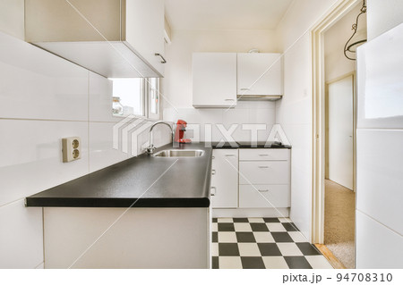 Well organized small home kitchen interior with sink under window and light furniture with stove and fridge in urban apartment Well organized small home kitchen interior with sink under window and light furniture with stove and fridge in urban apartment 94708310