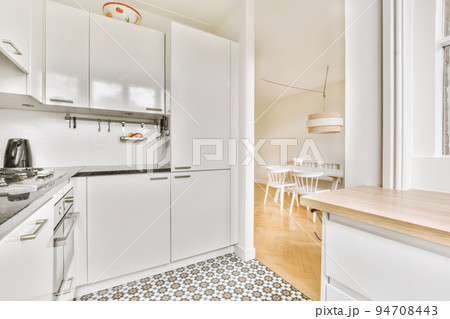 Well organized small home kitchen interior with sink under window and light furniture with stove and fridge in urban apartment Well organized small home kitchen interior with sink under window and light furniture with stove and fridge in urban apartment 94708443