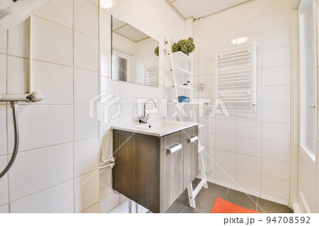 Sinks with mirrors and shower box with glass door in modern bathroom with white tiled walls Sinks with mirrors and shower box with glass door in modern bathroom with white tiled walls 94708592