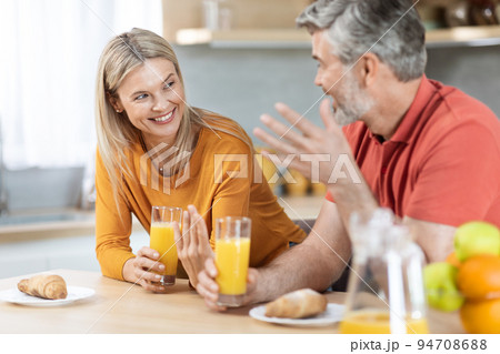 Happy loving spouses having conversation while eating at kitchen Happy loving spouses having conversation while eating at kitchen 94708688