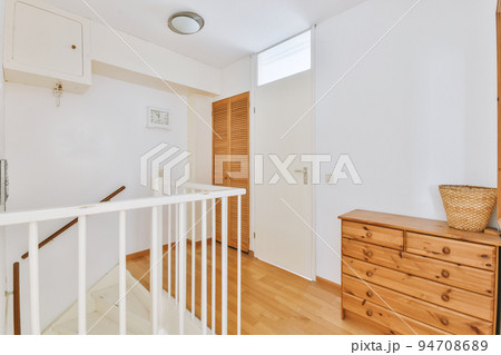 Closed white door of room located near framed pictures and stylish lamp on top of stairway at home Closed white door of room located near framed pictures and stylish lamp on top of stairway at home 94708689
