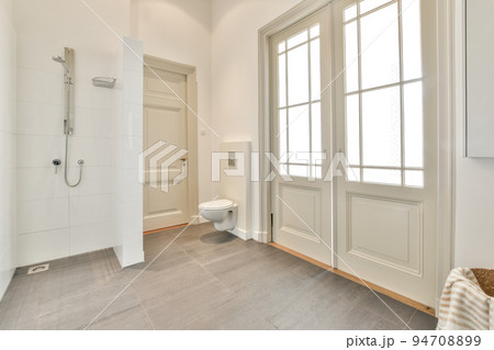 Glass partition between shower tap and wall hung toilet in modern restroom at home 94708899