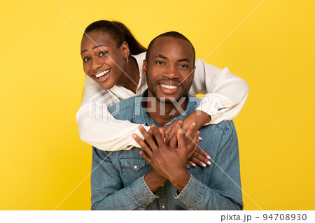 Cheerful African American Couple Embracing Posing Over Yellow Background 94708930