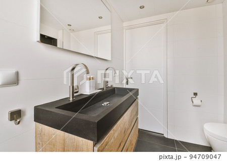 Flush toilet located between sink and shower in small tiled bathroom of contemporary apartment Flush toilet located between sink and shower in small tiled bathroom of contemporary apartment 94709047