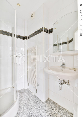 Sinks with mirrors and shower box with glass door in modern bathroom with white tiled walls Sinks with mirrors and shower box with glass door in modern bathroom with white tiled walls 94709110