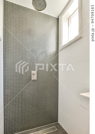 Glass partition between shower tap and wall hung toilet in modern restroom at home 94709165