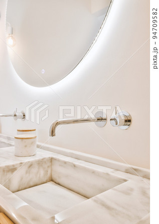 Sink with tap and liquid soap hanging on tiled wall under mirror in contemporary restroom at home Sink with tap and liquid soap hanging on tiled wall under mirror in contemporary restroom at home 94709582