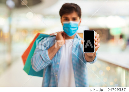 Man Showing Phone Screen Wearing Face Mask Shopping In Mall Man Showing Phone Screen Wearing Face Mask Shopping In Mall 94709587