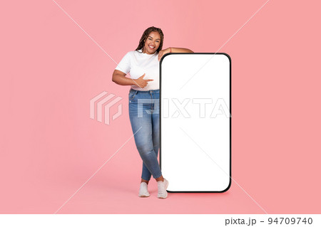 African American Female Pointing At Large Smartphone Screen In Studio 94709740