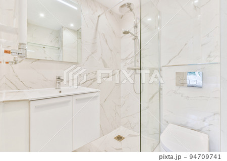 Sinks with mirrors and shower box with glass door in modern bathroom with white tiled walls 94709741