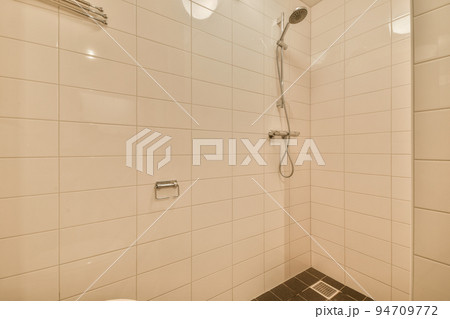 Modern flush toilet and ceramic sink installed on white tiled walls near mirror and towel in small restroom at home Modern flush toilet and ceramic sink installed on white tiled walls near mirror and towel in small restroom at home 94709772