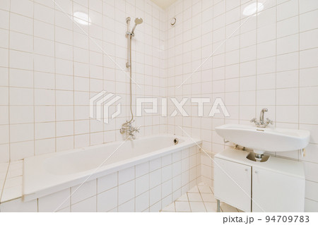 Sinks with mirrors and clean bathtub in modern bathroom with white tiled walls Sinks with mirrors and clean bathtub in modern bathroom with white tiled walls 94709783