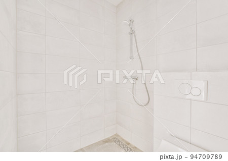 Shower faucets attached to tiled wall near glass partition and ornamental curtail in washroom at home Shower faucets attached to tiled wall near glass partition and ornamental curtail in washroom at home 94709789