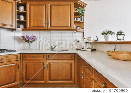 Fragment of interior of light narrow home kitchen with minimalist style white furniture with sink and stove Fragment of interior of light narrow home kitchen with minimalist style white furniture with sink and stove 94709900