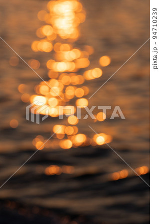 Blurred ripple sea ocean water surface with golden sunset light. Blurry sea wave close up with bokeh Blurred ripple sea ocean water surface with golden sunset light. Blurry sea wave close up with bokeh 94710239