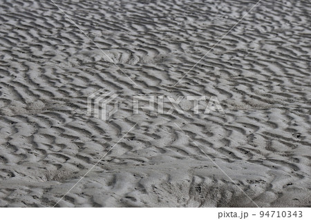 波紋とカニの巣の穴のたくさんある砂浜の風景 94710343