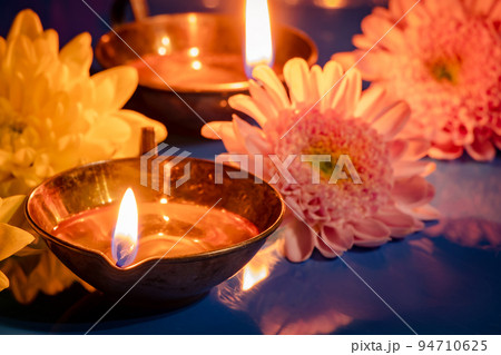 Happy Diwali. Burning diya oil lamps and flowers on blue background. Traditional Indian festival of light. Happy Diwali. Burning diya oil lamps and flowers on blue background. Traditional Indian festival of light. 94710625