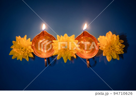 Happy Diwali. Diya oil lamps and yellow flowers on blue background. Celebrating the traditional Indian holiday of light. Happy Diwali. Diya oil lamps and yellow flowers on blue background. Celebrating the traditional Indian holiday of light. 94710626