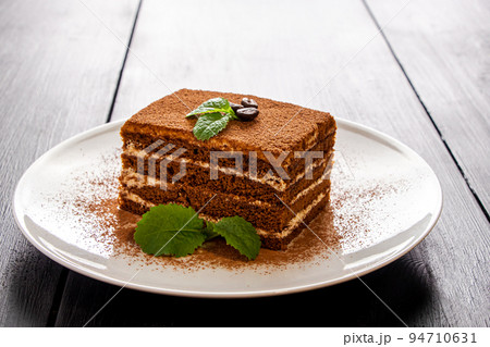 Tiramisu dessert decorated with mint on white plate. Tiramisu dessert decorated with mint on white plate. 94710631
