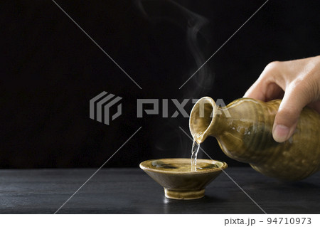 酒を注ぐ、熱燗の日本酒と酒器、徳利とお猪口 94710973