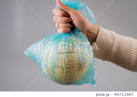 A woman is holding a globe in a plastic bag on a white background.  94711067