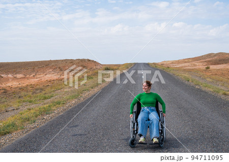 Woman in a wheelchair on a highway in the steppes.  94711095