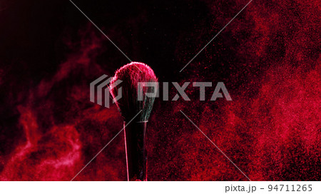 Makeup brush with an explosion of red powder on a black background. Makeup brush with an explosion of red powder on a black background. 94711265