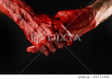 Man rubbing bloody hands on black background. 94711408