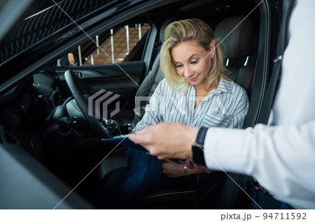 Happy caucasian woman signing a contract to buy a car. Happy caucasian woman signing a contract to buy a car. 94711592