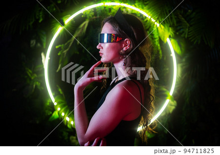 Caucasian woman in panoramic sunglasses against the background of an annular neon lamp in plants.  94711825